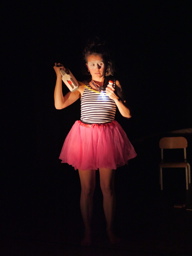 photo d'élodie marguerite, le radio K7 à la main et le micro dans l'autre, tutu rose et peinture blanche en bandeau sur les yeux